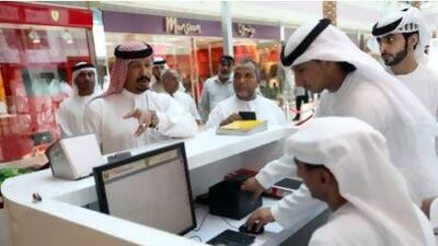 Marwan Al Hemyari, left, waits while Mohammed Al Shehhi, centre, and Faisal Saleh, both with the Ministry of Interior register Marwan for e-boarder system at Marina Mall in Abu Dhabi. Sammy Dallal / The National