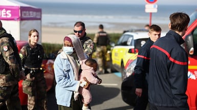 A woman and baby alongside rescue units after an attempt to cross the English Channel turned tragic. AFP