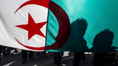 Demonstrators are silhouetted against a national Algerian flag as they stage a protest on the Republique Plaza in Paris, France, Sunday, March 17, 2019. AP