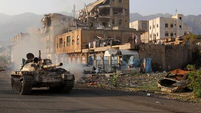 Pro-government forces ride a tank past a destroyed building in Taez in May. AFP