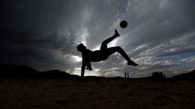 A Yemeni boy kicks the ball in the air during a football match among friends and neighbours in the capital Sanaa on April 11, 2018. A shock winning streak has propelled Yemen's youth and men's football teams to the Asian Cup, capturing the nation's attention and offering a common goal to a divided country. Mohammed Huwais / AFP