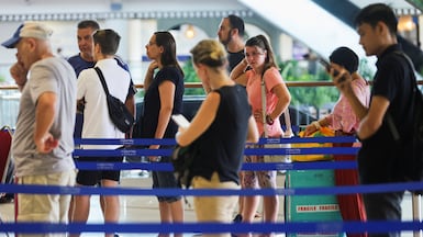 Stranded passengers wait at the Qatar Airways customer service at I Gusti Ngurah Rai International Airport on March 1, 2026, after flights to Doha, Dubai, and Abu Dhabi were cancelled following strikes on Iran launched by the US and Israel. Reuters