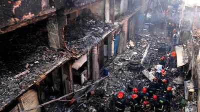 Locals and firefighters gather around buildings that caught fire late Wednesday in Dhaka, Bangladesh, Thursday, Feb. 21, 2019. A devastating fire raced through at least five buildings in an old part of Bangladesh's capital and killed scores of people. (AP Photo/Rehman Asad)