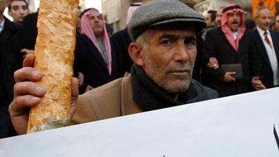 A Jordanian man brandishes a loaf of bread with a sign reading 'No for price rises', during a protest against rising prices, in Amman, Jordan.