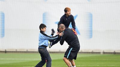 Dani Alves of FC Barcelona greets young fans who ran onto the training pitch during a Barcelona training session ahead of the Uefa Champions League round of 16 second leg match between Barcelona and Arsenal at Ciutat Esportiva on March 15, 2016 in Barcelona, Spain. (Photo by David Ramos/Getty Images)