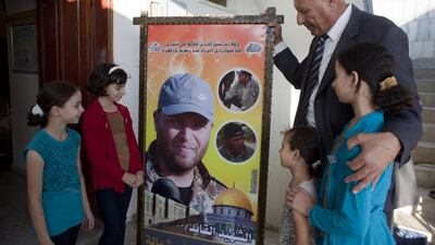 Fayez Abu Shammala, 63, with his children, holds a poster of his 32-year-old son Hazem, who he only discovered after his death that he was a fighter in in the Islamic Jihad. Hazem was killed by a mortar shell while fighting Israeli soldiers in the eastern Qarrarah area near the southern city of Khan Younis, Mr Abu Shammala said. Heidi Levine for The National