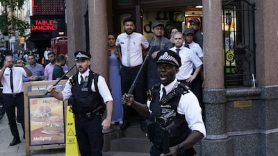 Police officers armed with batons outside a McDonald's store. PA