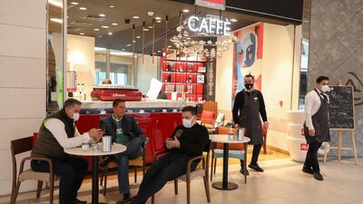 Men sit at an Illycaffe inside a shopping mall that has reopened, as the Covid-19 restrictions are eased, in Beirut. Reuters