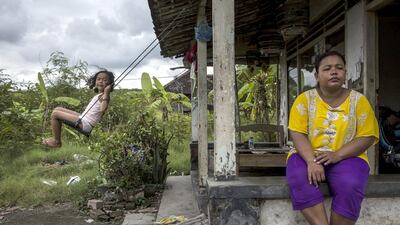 Fitriani, and her daughter Azizah, play in front of their house which was partially destroyed by the mudflow when it hit Merisen Village. Ten years on, more than 100 families have yet to receive compensation. Ulet Ifansasti / Getty Images