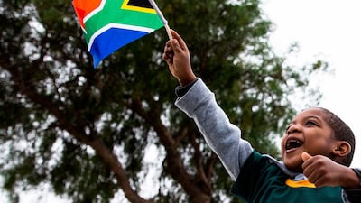 A young Springboks supporter, wearing a jersey with the South African Rugby captain Siya Kolisi's name written on, waves a South African national flag as the South African Rugby World Cup winner team parades on an open top bus. AFP