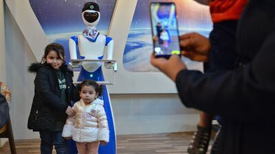 Children pose for a picture next to a robot waiter at the "White Fox" restaurant in the eastern part (left bank of the Tigris river) of Iraq's northern city of Mosul, on November 17, 2021. AFP