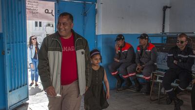 A Tunisian policeman dressed in civilian clothing arrives with his daughter at a polling station for the police and military in Tunis, Sunday, April 29, 2018. This is the first time in Tunisian history that the military and police have participated in municipal elections. Hassene Dridi / AP