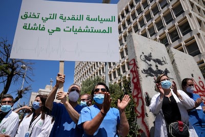 A nurse holds an Arabic placard that reads: "Monetary policy that stifles hospitals is a failure," as he protests with other medical workers and doctors the deteriorating economic conditions in Lebanon. AP
