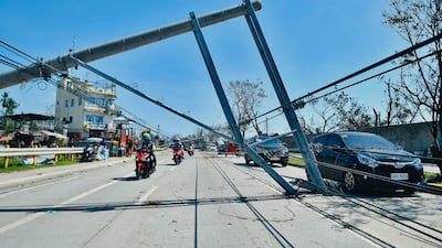 Motorists drive past an electricity pylon damaged by Typhoon Rai in Talisay, Cebu province, in the Philippines. AFP