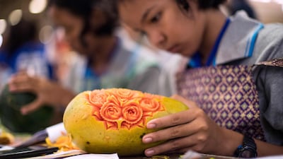 A Thai girl carves floral patterns into a papaya during a fruit and vegetable carving competition in Bangkok. Robert Schmidt / AFP