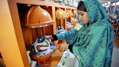 An employee holds a hose inserted into the valve of an Adidas AG "Brazuca" football in a thermo-bonding molding machine on the production line at the Forward Sports Ltd factory in Sialkot, Punjab. Asad Zaidi/Bloomberg