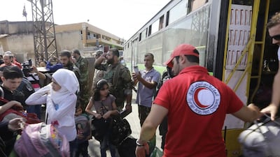 Members of the Syrian Red Crescent help the families of opposition fighters at a Syrian army checkpoint on the edge of the rebel-held Waer neighbourhood in the central city of Homs during an evacuation operation on September 22, 2016. Under a deal with the Syrian government, an estimated 150 rebels and their families are being evacuated from Waer to northern parts of Homs province. UN organisations, which had helped oversee previous evacuations from Waer, were not involved in this operation. Louis Beshara / AFP