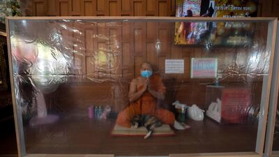 A Buddhist monk prays behind plastic sheets during the Thai New Year at the Samian Nari Temple in Bangkok. AP