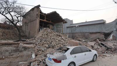 Collapsed buildings and a damaged car in Dahejia village. AFP