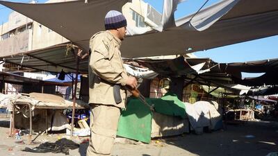 A guard stands near the entrance of a market close to the scene of a car bomb near St John’s church during Christmas Mass in Dora, Baghdad. Ali Al Saadi / AFP