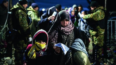 A woman and child walk past Macedonian police officers, as migrants and refugees cross the Greece-Macedonia border in November near Gevgelija. Over 200 migrants on November 26 tried to break through barbed wire fences to cross from Greece into Macedonia, which imposed new border restrictions. Robert Atanasovsi / AFP