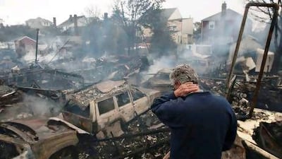 A resident looks over the remains of burned homes in the Breezy Point neighbourhood of New York. Hurricane Sandy will have caused $20bn in property damage and up to $30bn more in lost business.