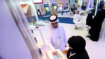 Ahmed Al Madhloum of Sharjah Islamic Bank helps Rabah Al Ansari with her application at the exhibition. Satish Kumar / The National