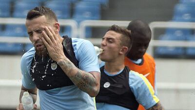 Manchester City’s Nicolas Otamendi, left, splashes water on himself to cool down during the team’s training session at the Olympic Sports Center Stadium in Beijing, Sunday, July 24, 2016. Mark Schiefelbein / AP Photo