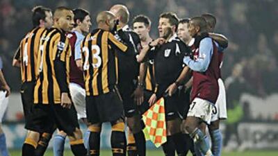 Players surround the referee Steve Bennett as he backtracks on his original decision to give a penalty to Hull after he consulted his assistant.