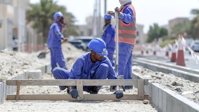 Road workers protect themselves with scarfs from the heat while doing roadworks at Khalifa City. Victor Besa / The National