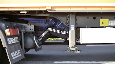 A migrant sits under the trailer of a lorry as he attempts to cross the English Channel, in Calais, northern France to Britain on Wednesday, June 24, 2015. Thibault Camus/AP Photo