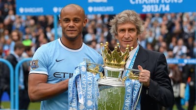 Manchester City midfielder Vincent Kompany and Manchester City Manuel Pellegrini hold the Premier League trophy after winning 2-0 against West Ham United at the Etihad Stadium on Sunday. Andrew Yates / AFP