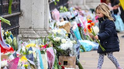 A girl lays flowers as tribute to Prince Philip outside Buckingham Palace, in London. Getty Images