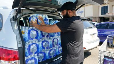 Rajwinder Singh crams 15 cases of drinking water into his vehicle. AP