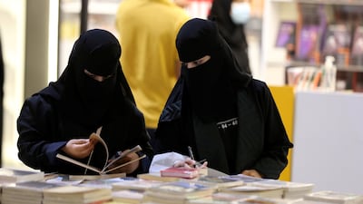 Two Saudi women look at a book during the Riyadh International Book Fair.