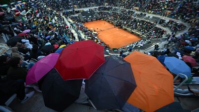 Spectators shelter from rain that interrupted a match between Stefanos Tsitsipas and Lorenzo Sonego at the Rome Open tennis tournament. AFP