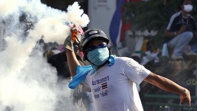 A Thai anti-government protester throws a tear gas canister back to police during a street battle to occupy Government House in Bangkok. Rungroi Yongrit / EPA