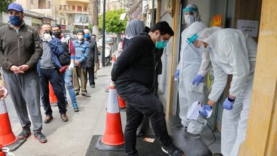 Workers wearing protective gear spray disinfectant on customers before entering a supermarket, during a lockdown to prevent the spread of coronavirus in Beirut, Lebanon. Reuters