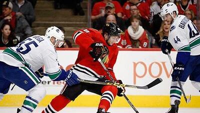 Chicago Blackhawks right wing Patrick Kane, No 88, skates past Vancouver Canucks defenceman Alex Biega, No 55, and defenceman Matt Bartkowski, No 44, during the second period of their NHL game in Chicago on Sunday. Andrew A Nelles / AP Photo
