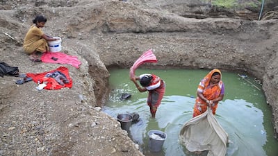 Women wash clothes using water from a pond. Subhash Sharma for The National