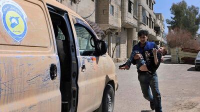 This photo released by the Syrian Civil Defense White Helmets, shows a member of the Syrian Civil Defense group carrying a boy who was wounded during airstrikes and shelling by Syrian government forces in Ghouta, a suburb of Damascus, Syria, Sunday, March. 11, 2018. President Donald Trump has announced a freezing of US funding for the group. Syrian Civil Defense White Helmets via AP