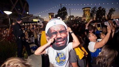A man holds up an image of Cleveland Cavaliers' LeBron James crying as fans celebrate outside Oracle Arena in Oakland California. Josh Edelson / AP Photo