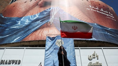 A woman holds an Iranian flag in front of an anti-US billboard in Tehran on Monday. Reuters