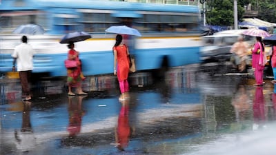 Indian commuters cross a street during monsoon showers in Kolkata. Piyal Adhikary / EPA