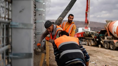 Israeli workers lay concrete while working on the border wall. AFP