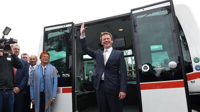 Richard Lutz, CEO of German railway company Deutsche Bahn, waves in front of the first German autonomous public transport bus during a presentation in Bad Birnbach, southern Germany, on October 25, 2017. German state-owned rail company Deutsche Bahn unveiled its first-ever driverless bus Wednesday, saying the shuttle will bring passengers through a picturesque spa town to the train station. The first autonomous minibus can transport six passengers. It will travel on a partial public transport route of 700 meters in the small town of Bad Birnbach Lower Bavaria. / AFP PHOTO / Christof STACHE