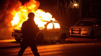 A riot policeman passes by a burning police vehicle in Ferguson, Missouri. Alex Furman / EPA