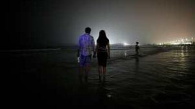 A married couple shares a romantic walk on the public beach near the Jumeriah Beach hotel in Dubai.