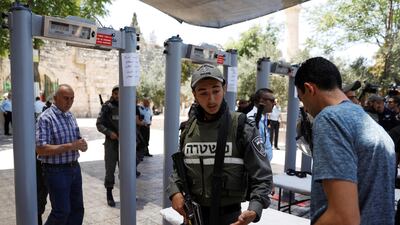 An Israeli border police officer asks to check the identity of a Palestinian man next to newly installed metal detectors at an entrance to the compound known to Muslims as Noble Sanctuary and to Jews as Temple Mount to be reopened, in Jerusalem's Old City. Ronen Zvulun / Reuters