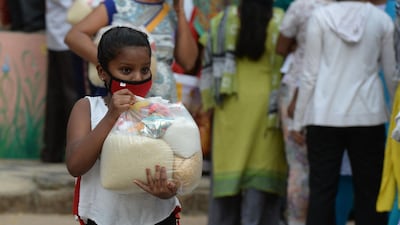 A girl carries food distributed for people in need during a coronavirus lockdown, at Saint Marys Basilica in Secunderabad, India. AFP